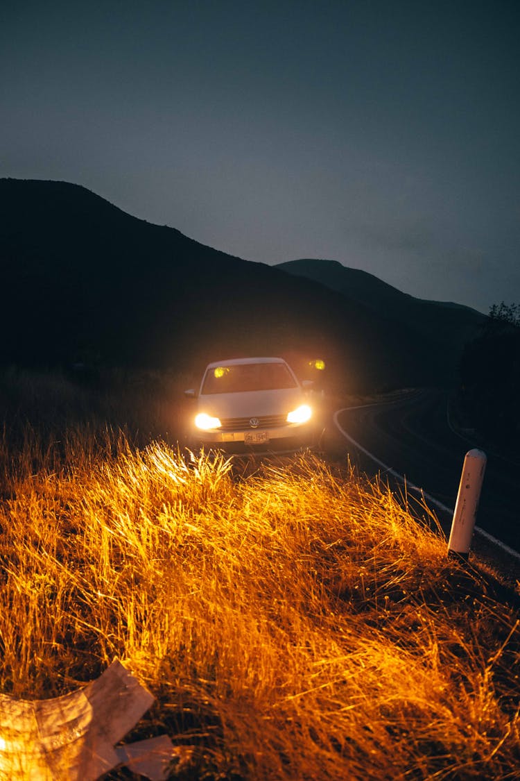 Car Headlights Illuminating Hill At Night