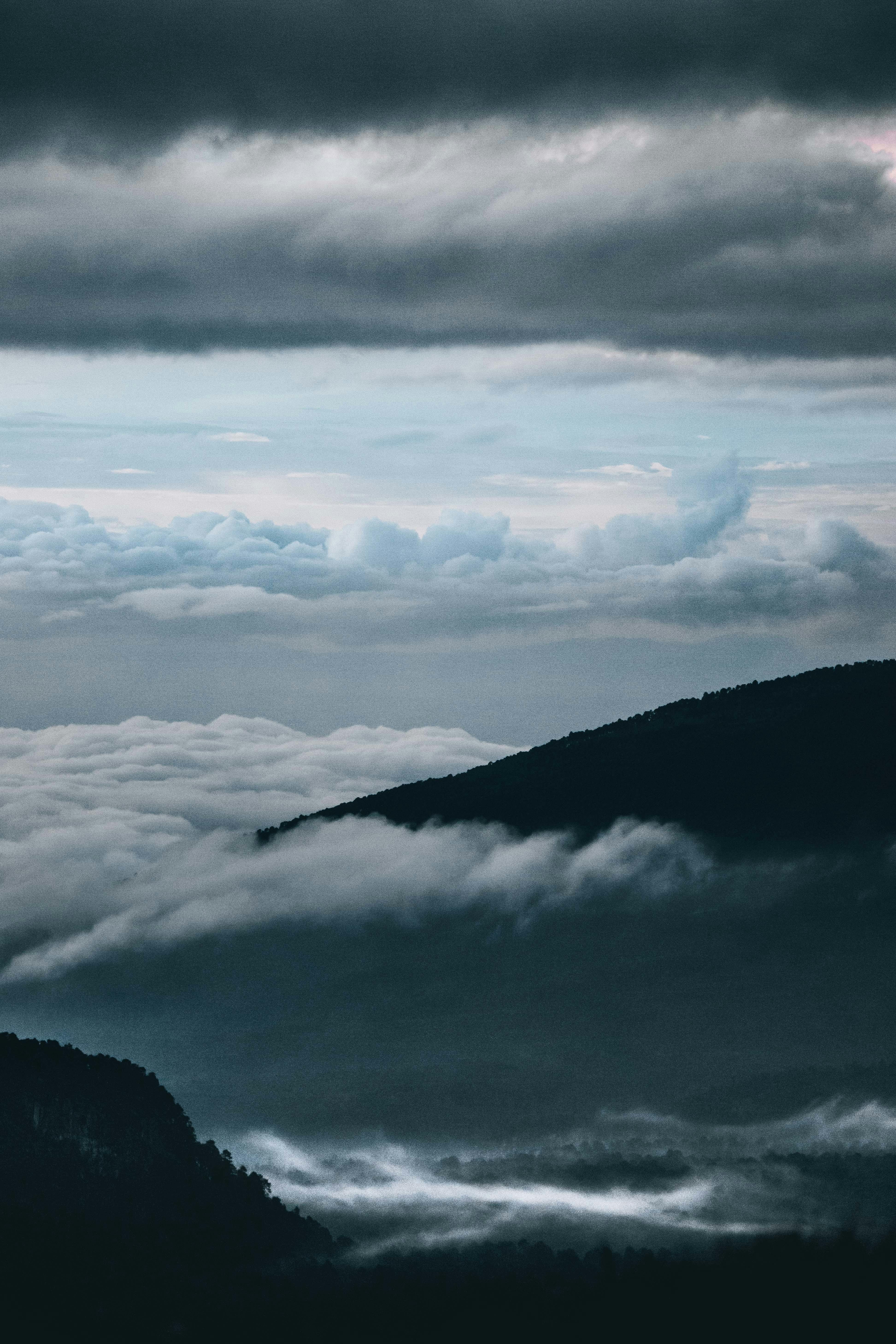 Breathtaking view of mountains engulfed in a mystical sea of clouds and dramatic sky.