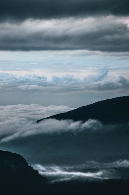 Breathtaking view of mountains engulfed in a mystical sea of clouds and dramatic sky.