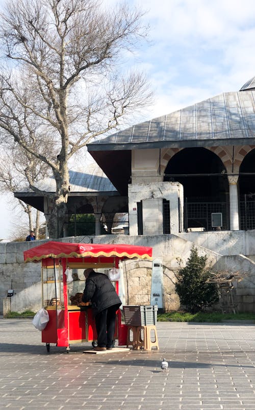 Photo of a Vendor with a Red Cart Near a Building