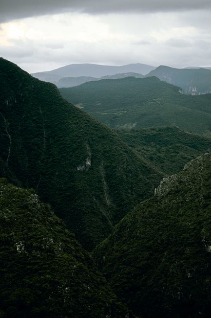Dramatic view of lush green mountains with cloudy skies, creating a serene and picturesque nature scene.