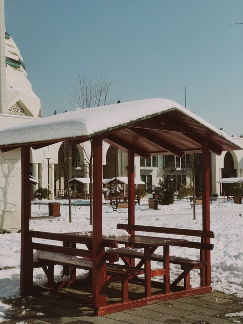 Free A red gazebo covered with snow in a quiet winter park under a blue sky. Stock Photo