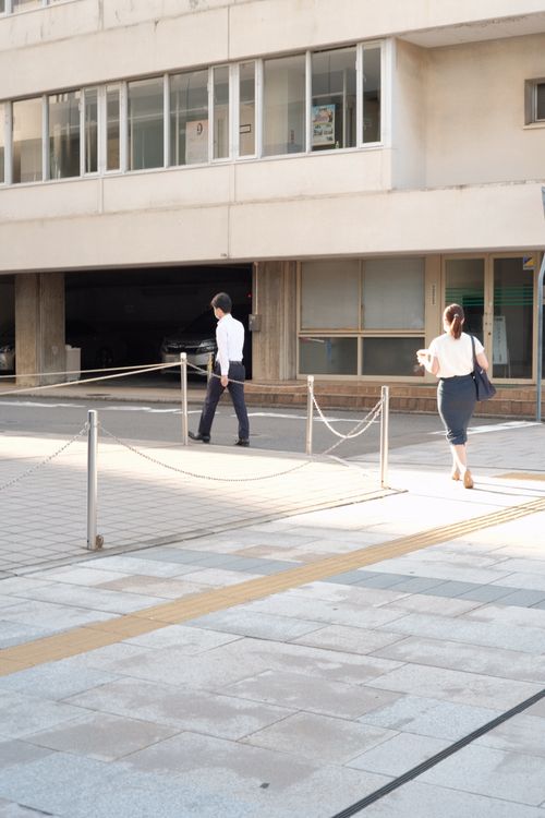 Free Two people walking outside an office building on a sunny day. Stock Photo