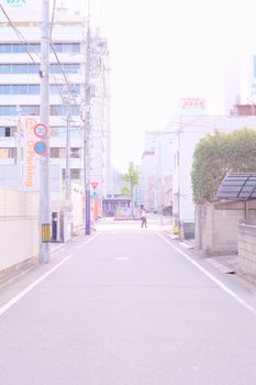 Daytime view of a quiet urban street with buildings and signage in a soft light.