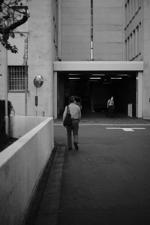 Free Monochrome image of a person walking towards a building in a city street. Stock Photo