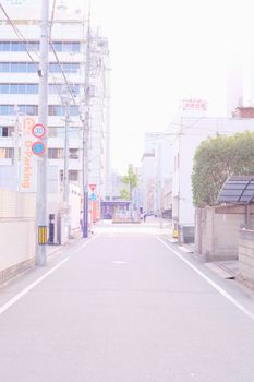 Bright daylight view of a city street lined with buildings and trees, creating a serene urban scene.