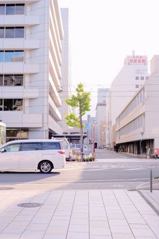 Sunlit urban street scene capturing modern buildings and parked cars.
