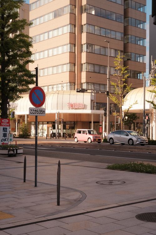 Free City street in Japan featuring modern buildings and a no entry sign with cars passing by. Stock Photo