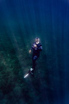Scuba diver in the Philippines exploring underwater depths, surrounded by sea life and bubbles.