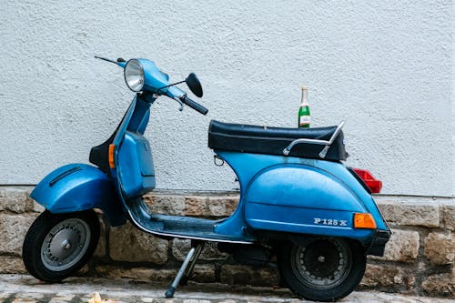 A Blue Scooter Parked Near a White Wall