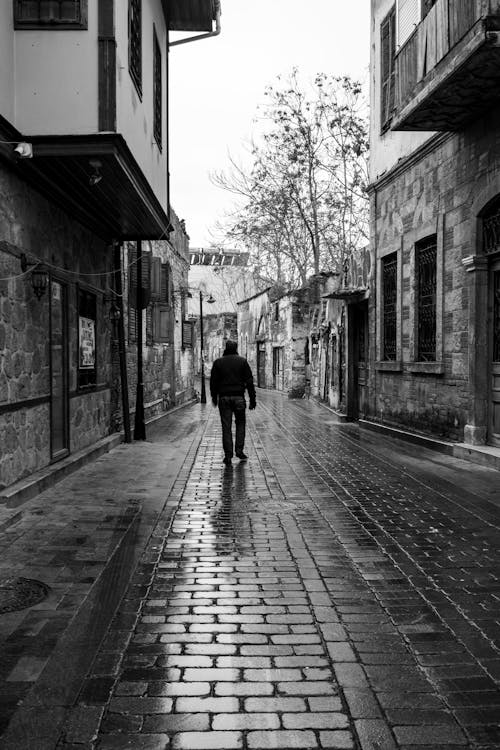 Grayscale Photo of Person Walking on the Street