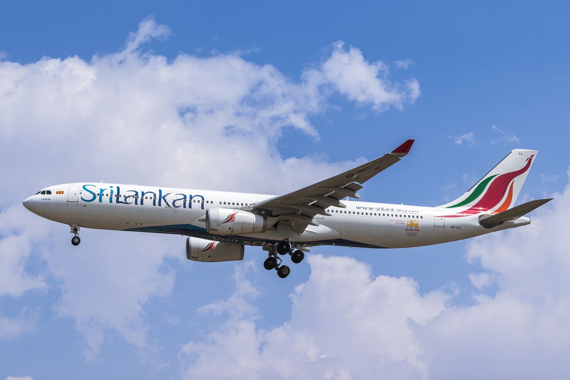 SriLankan Airlines Airbus A330 flying against a bright blue sky with fluffy clouds.