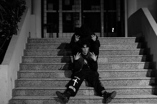 Grayscale Photo of Men Posing on Concrete Stairs