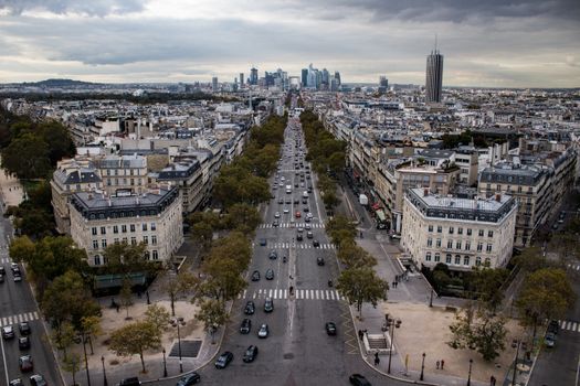 Aerial shot of Paris, featuring city streets, classic architecture, and cars under cloudy skies.