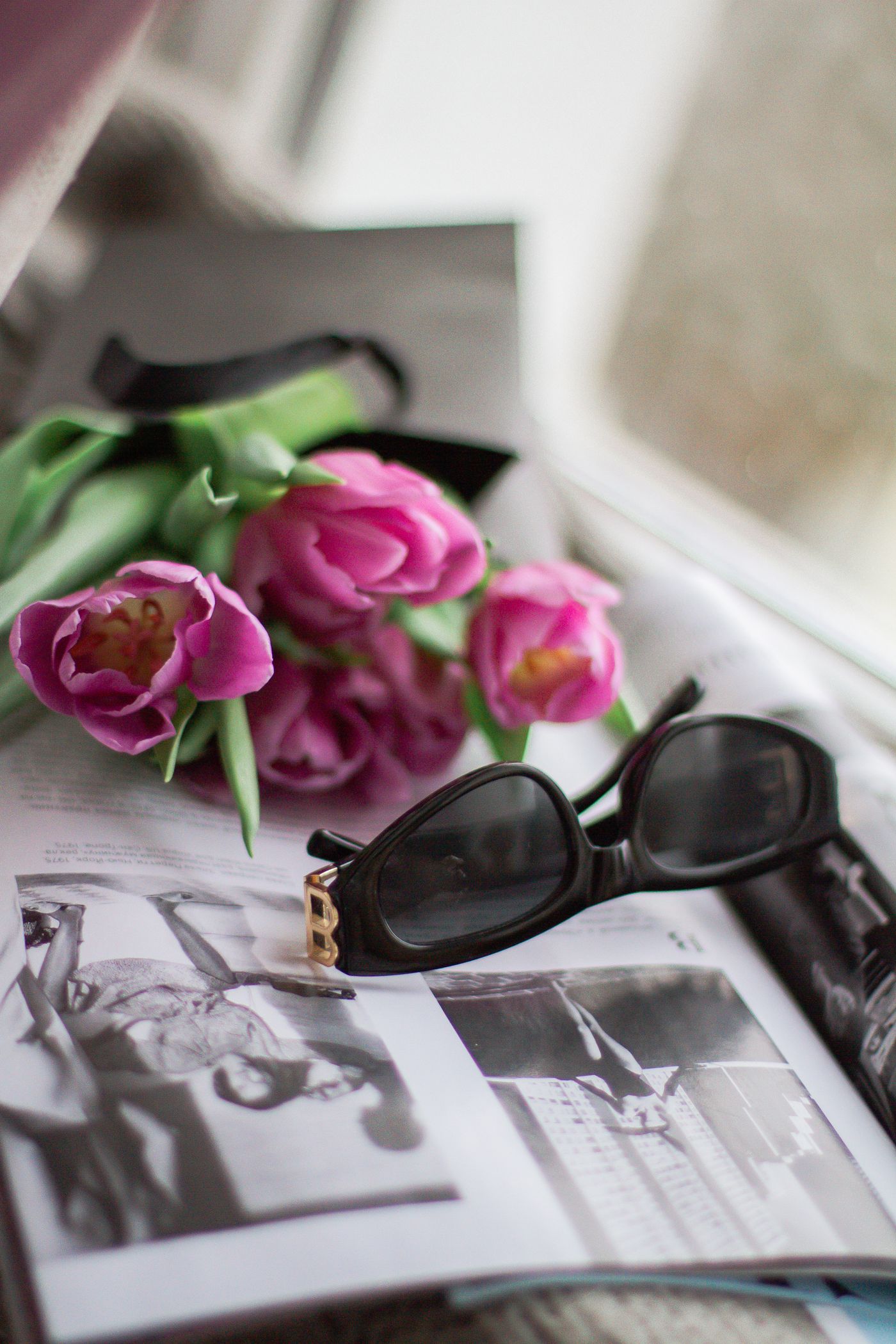 Black-framed sunglasses resting on an open magazine — the editorial accessory