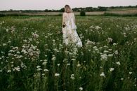 Woman in White Dress Standing on Green Grass Field