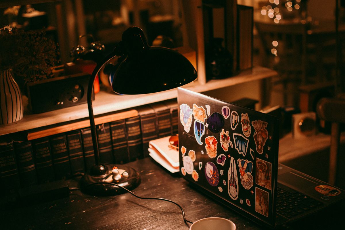 A warmly lit desk with a laptop and vintage tools, Svetlana Tumina on Pexels