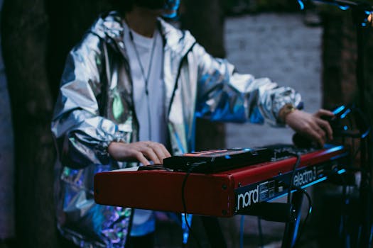 A musician wearing a silver jacket plays a synthesizer in an atmospheric setting.