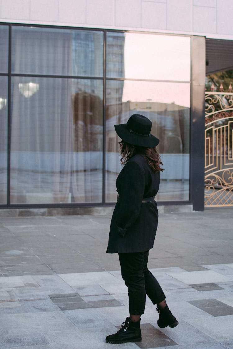 A Woman In Black Outfit Looking At The Glass Window