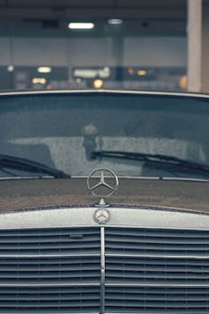 Vintage Mercedes-Benz car with rain-soaked emblem showcasing classic elegance.