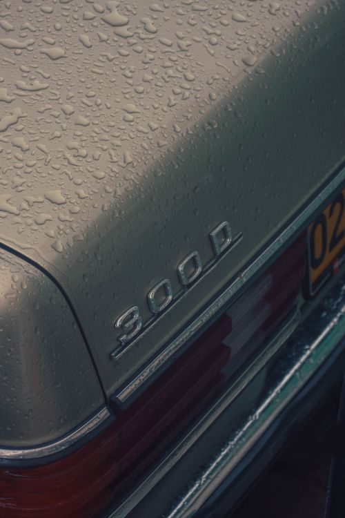 Free Close-up of a vintage Mercedes 300D car emblem covered in rain droplets, creating a classic moody look. Stock Photo