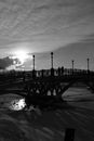 Grayscale Photo of Bridge Under Cloudy Sky