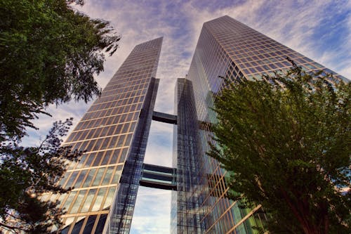Free 在湛蓝的天空下的两个透明玻璃摩天大楼的低角度照片 Stock Photo