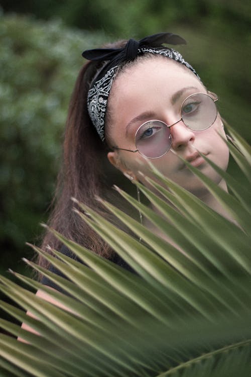 A Woman Posing behind a Palm Leaf