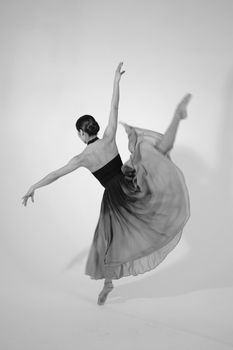 Black and white photo capturing a graceful ballet dancer in mid-jump, showcasing elegance and movement.