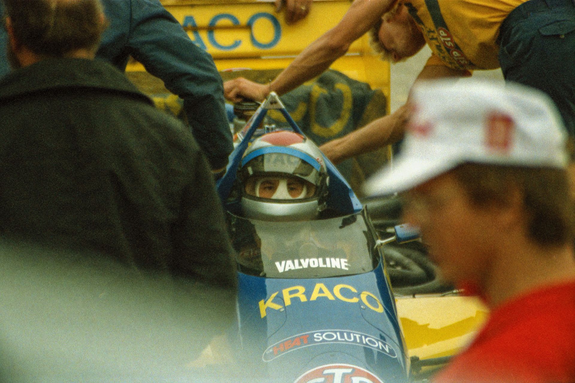 Driver in a racecar preparing for competition at Elkhart Lake with crew around.