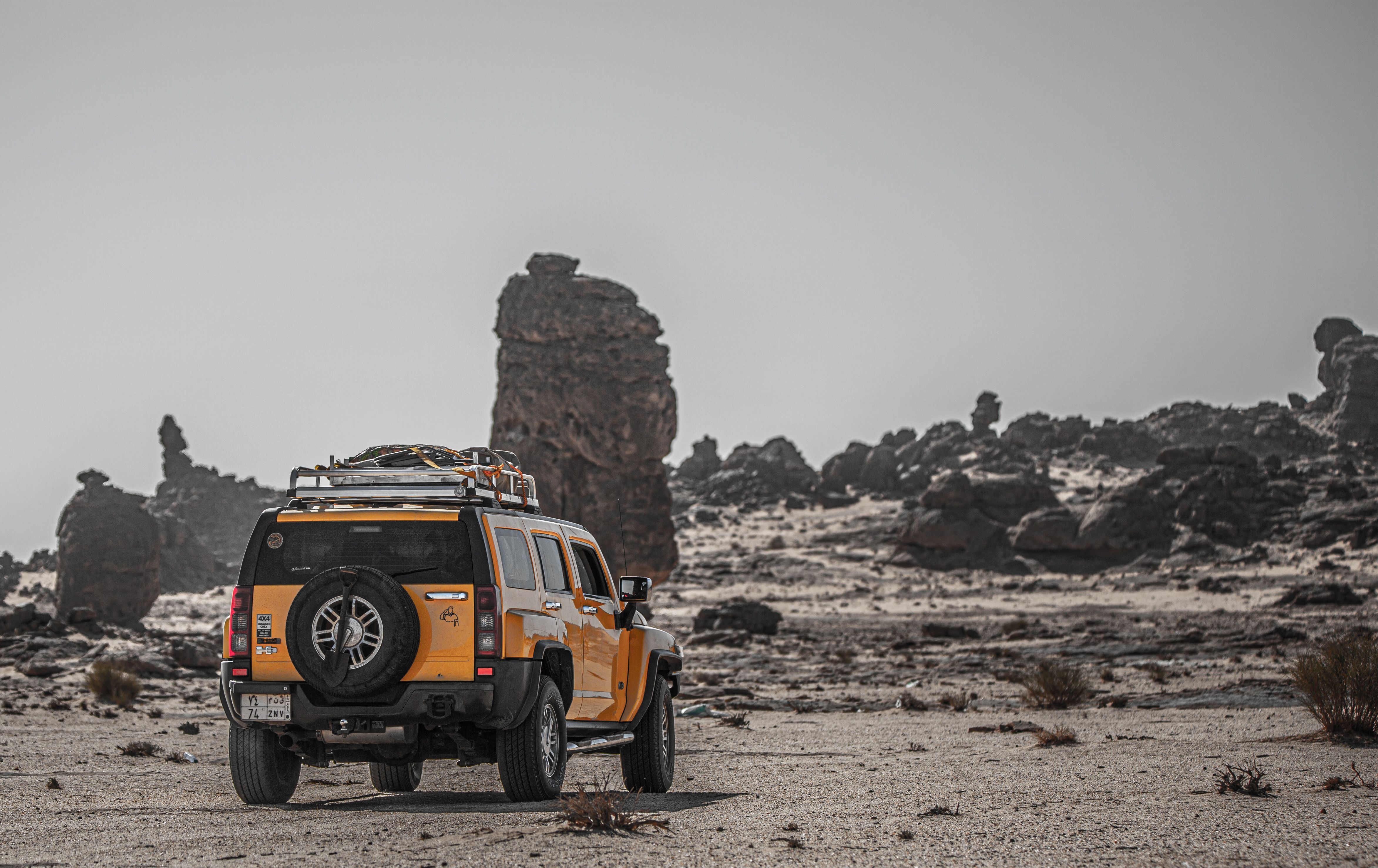 Yellow SUV exploring rugged desert terrain with rocky formations