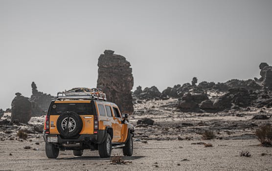 Yellow SUV exploring rugged desert terrain with rocky formations.