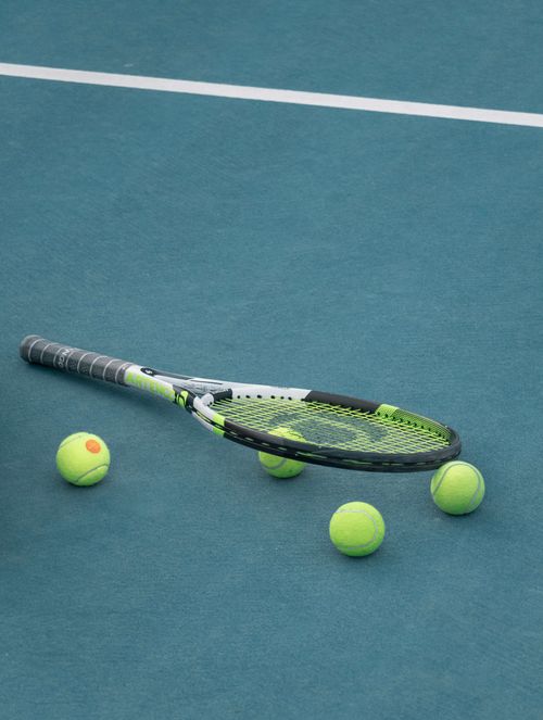 Free Tennis racket and balls on a blue court surface under day light. Stock Photo
