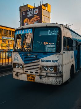 Old city bus on a road with a billboard in the background during the day.