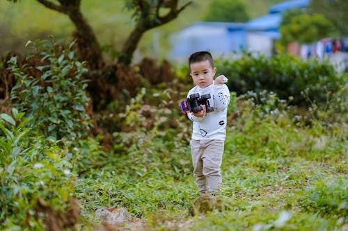 Child in a White Long Sleeve Shirt Holding a Toy Car