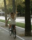 Woman in White Long Sleeve Shirt Riding Bicycle on Road