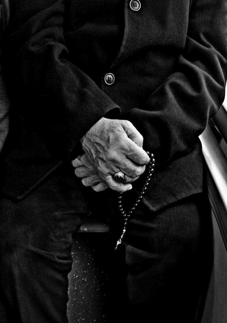 Elderly Man In Public Transport Holding A Rosary