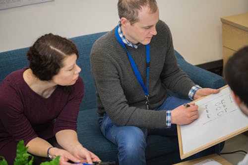 Man Writing on a Whiteboard Near a Woman