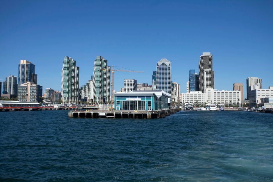 Skyline of a modern city with skyscrapers and a waterfront under a clear blue sky.