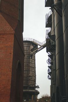 Vertical view of brick and metal industrial towers in an urban setting.