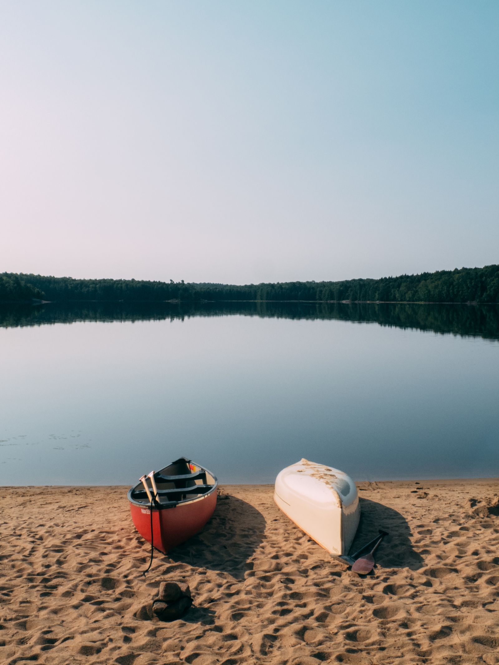 Canoes on the calm lake shore at dusk