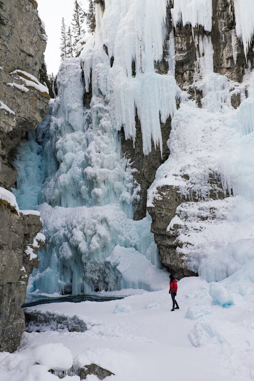 Free Woman Under a Frozen Waterfall  Stock Photo