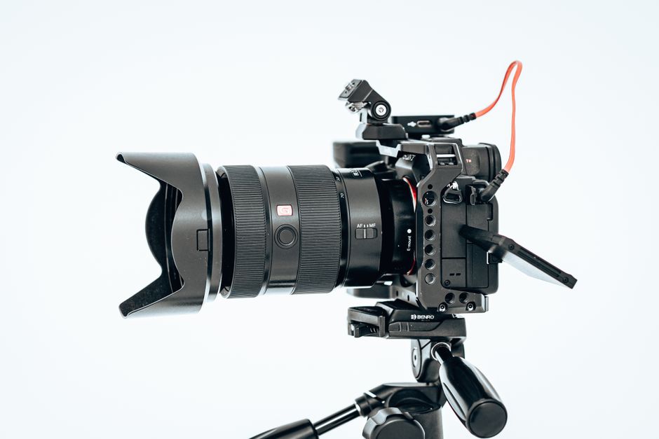 Close-up of a professional camera setup on a tripod with lens hood and cables.