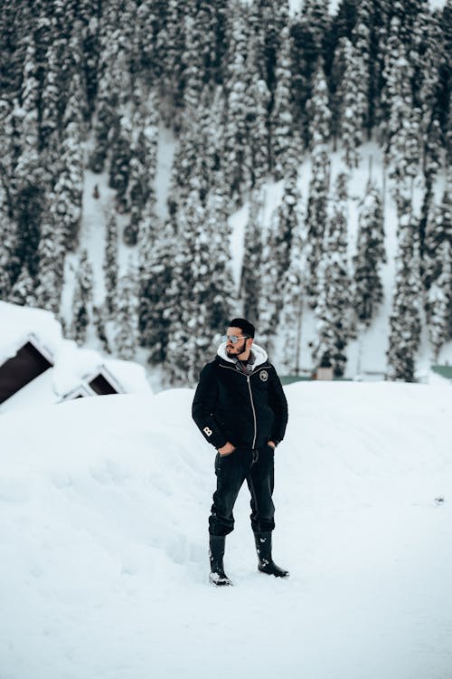 Bearded Man in Black Jacket Standing on Snow Covered Ground