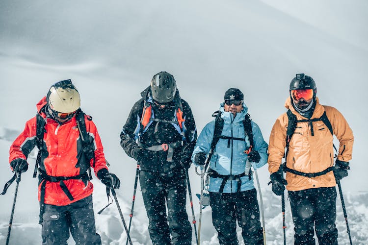 A Group Of Men Skiing In Snow