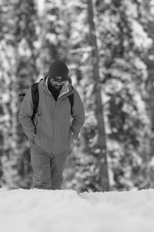 Grayscale Photo of a Man Walking while His Hands are in His Pockets