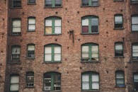 一座带有绿色窗框的复古城市砖砌建筑，其外观细节展现出浓郁的复古城市氛围