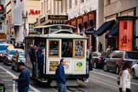 标志性的旧金山缆车载着乘客，在充满活力的城市街道上穿行，展现了交通与城市生活的风貌