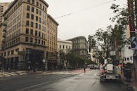 阴天的街道上，历史建筑旁车辆行人往来，充满活力