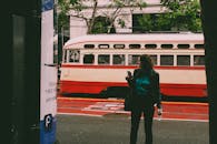 一名妇女站在繁华城市里的一辆老式红色有轨电车旁